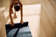 © Drazen - Above view of woman unrolling exercise mat while preparing to workout in Yoga studio.