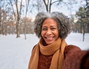 Wall Mural - Portrait of Beautiful Happy Black Woman Outdoors in Park During Winter Taking Selfie