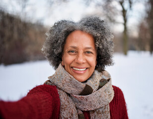 Wall Mural - Portrait of Beautiful Happy Black Woman Outdoors in Park During Winter Taking Selfie