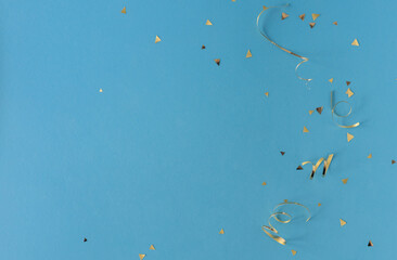Wall Mural - close up on group of gold color of rolling ribbon and confetti on teal background with copy space fo