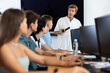 © JackF - Positive adult male teacher guiding group of interested young people attending computer class and learning digital technology