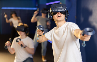 man in virtual reality glasses and with joystick plays exciting shooter game with friends. technolog