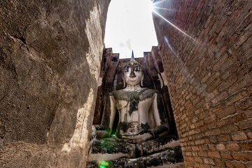 Wall Mural - The background of one of the important tourist attractions in Sukhothai Historical Park, Wat Si Chum, has a large Buddha statue that is hundreds of years old for tourists to learn about its history.