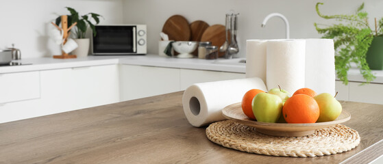 Sticker - Rolls of paper towels with fruits on table in kitchen, closeup