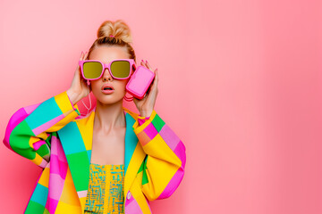 Wall Mural - A woman wearing a colorful outfit and sunglasses is holding a pink iPod