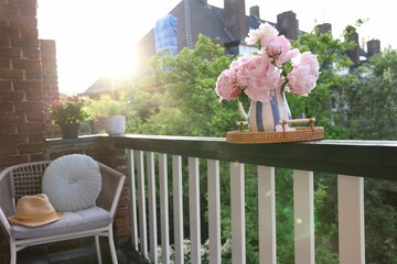 Sticker - Vase with beautiful peonies on railings and chair at cozy balcony on sunny day