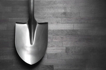 Metal shovel on black wooden table, top view. Space for text