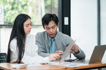 Wall Mural - Two professionals engaged in a discussion over documents in a contemporary office environment.