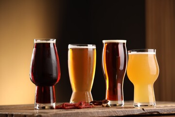 Wall Mural - Glasses with different types of beer and snacks on wooden table against color background