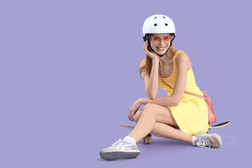 Sticker - Beautiful young woman in helmet sitting on skateboard against lilac background