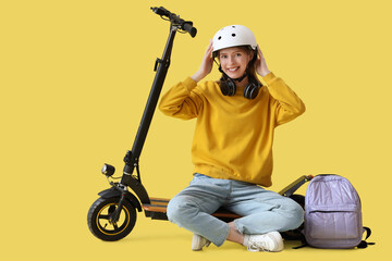 Sticker - Beautiful young woman in helmet with modern electric kick scooter sitting against yellow background