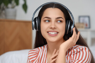 Wall Mural - Beautiful young happy woman in headphones listening music at home