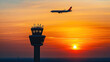 © Creativision - Silhouette of an airplane flying over the control tower at sunset
