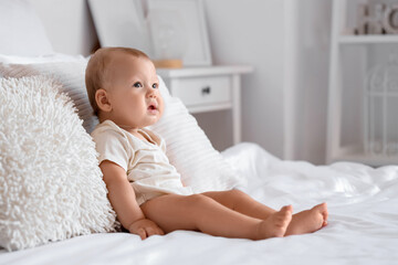 Sticker - Cute little baby sitting on bed in room at home