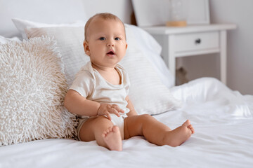 Sticker - Cute little baby sitting on bed in room at home