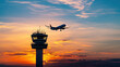 © Creativision - Silhouette of an airplane flying over the control tower at sunset