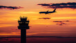 © Creativision - Silhouette of an airplane flying over the control tower at sunset