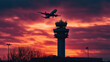 © Creativision - Silhouette of an airplane flying over the control tower at sunset