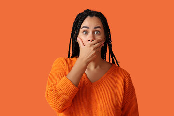 Sticker - Beautiful young shocked African-American woman covering mouth on orange background