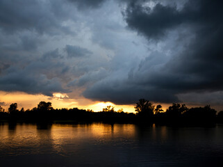 Stormy clouds over lake at sunset, showcasing climate change effects.