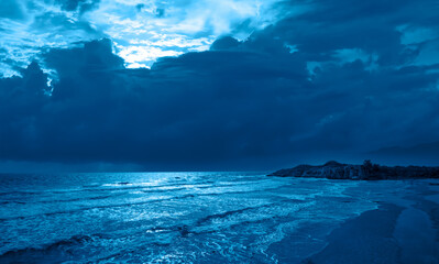 Wall Mural - Night sky with moon rising in the clouds over the calm blue sea