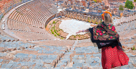 Wall Mural - Happy woman in a flowered headdress open arms in free happiness standing and posing - Roman amphitheater in ancient city of Ephesus - Selcuk, Turkey