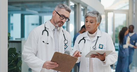 Leinwandbilder - Advice, discussion and doctors in hospital with clipboard, tablet or meeting for schedule in lobby. Results, man and woman together in healthcare with paperwork, consulting and medical team in clinic