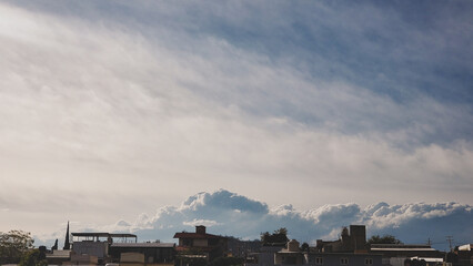 Wall Mural - View of a blue cloudy sky over city landscape.