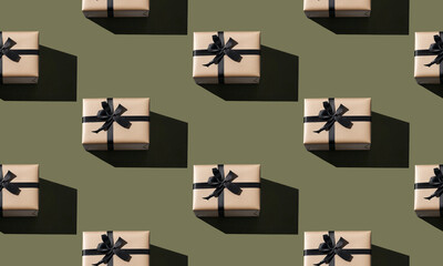 Seamless pattern made of craft gift boxes with black ribbons on a green background. Minimal and trendy composition pattern. Flat lay top view.