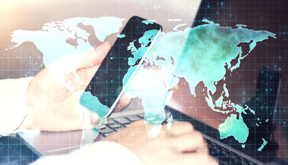 Wall Mural - Close up of businessman hands using laptop and cellphone with map hologram on blurry background. Travel and technology concept. Double exposure.