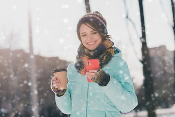 Poster - Photo of young charming happy woman hold look phone cup of coffee weekend walk snow outdoors outside