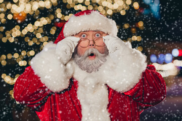 Canvas Print - Portrait of impressed santa claus pouted lips arms touch glasses staring cant believe midnight tree garland city center outside