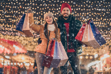 Wall Mural - Black friday. Photo of two people friends raise buy shopping bags under x-mas christmas outdoors evening lights wear winter outerwear