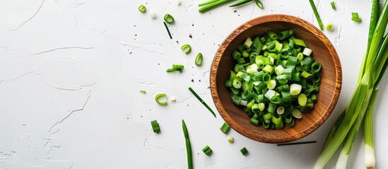 Aufkleber - A wooden bowl holds chopped spring onions on a white table providing ample copy space in the image