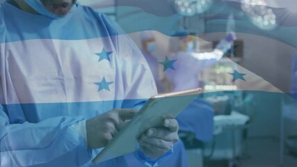 Canvas Print - Animation of flag of honduras over african american male surgeon using tablet in hospital