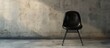 © HN Works - Old black chair sits alone on concrete floor with copy space image