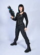 © faestock - Full length portrait of beautiful black female model with short black hair wearing sci fi futuristic dystopian leather bodysuit costume. Standing pose holding gun weapon, isolated white studio backgro