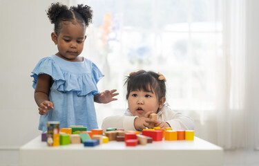 two diverse children playing with colorful wooden blocks early childhood education, learning and dev