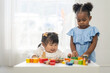 © Art_Photo - Two diverse children playing with colorful wooden blocks early childhood education, learning and development fun activities for kids in preschool, creative playtime, cognitive growth, friendship