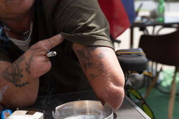 A closeup of an individual showcasing tattoos and lifestyle elements in an urban caf