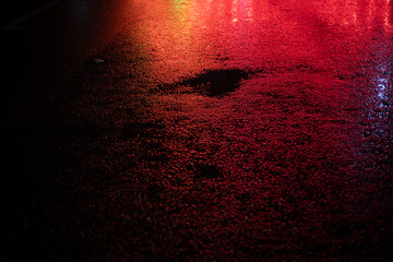 Red light on wet asphalt. Asphalt in a red glow in the evening. Empty parking space.