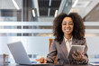 © Tetiana - Portrait of a smiling and successful African American businesswoman working in the office at a desk using a laptop and a tablet, looking confidently at the camera