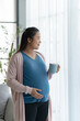 © mojo_cp - Pregnant woman hand touch on belly caring about baby health.