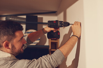 Wall Mural - Handyman with battery drill fixing kitchen cabinets and shelf.