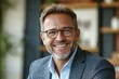 © JAYDESIGNZ - Happy middle aged professional business man, smiling mature executive ceo manager, 45 years old male entrepreneur, confident business owner wearing glasses in office. Headshot portrait