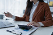 © Jirapong - woman meticulously plans a finance audit, using a computer and calculator to review budget documents and ensure accuracy