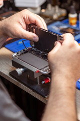 Fototapete - A technician carefully disassembles a smartphone to replace its battery in a well-equipped repair shop