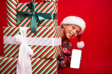 Sticker - Photo of charming small boy hide behind present pile qr code device celebrate christmas dressed knitted sweater isolated on red background