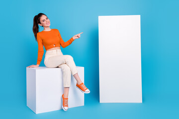 Wall Mural - Photo of good mood woman point finger long white board telephone promotion isolated on blue color background