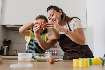 kid craking an egg when preparing food with mother